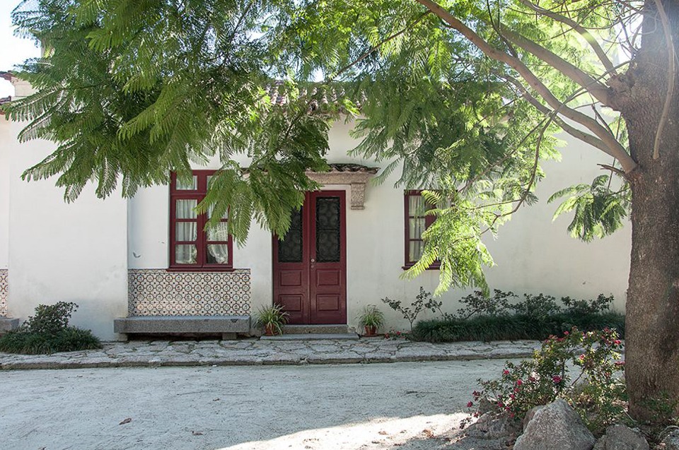 Porta encarnada da casa, sob a sombra de uma árvore