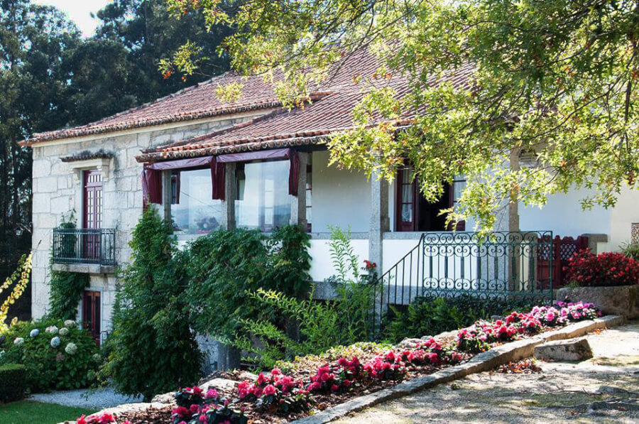 A casa de granito da Casa de Oleiros, com telhado de telha, varanda e jardim